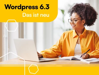 Eine Frau mit Brille sitzt an einem Tisch vor einem Laptop und einem Notizbuch; sie trägt ein orangefarbenes Hemd.