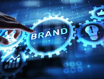 Eine Hand über einer leuchtenden Zahnradscheibe mit dem Wort BRAND, umgeben von weiteren Zahnrädern und digitalen Symbolen.