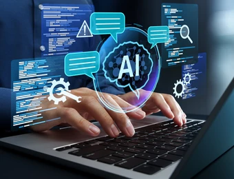 Hände tippen auf Laptop, holografische AI-Grafik mit Chatblasen, Zahnrädern und Codeblöcken über dem Display.