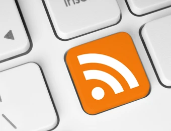 Nahaufnahme einer Computer-Tastatur; eine orangefarbene Taste mit RSS-Symbol, umgeben von weißen Tasten.