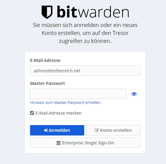 Bitwarden-Anmeldeseite mit Logo, Felder für E-Mail-Adresse und Master-Passwort, Checkbox und blauem Anmelden-Button.