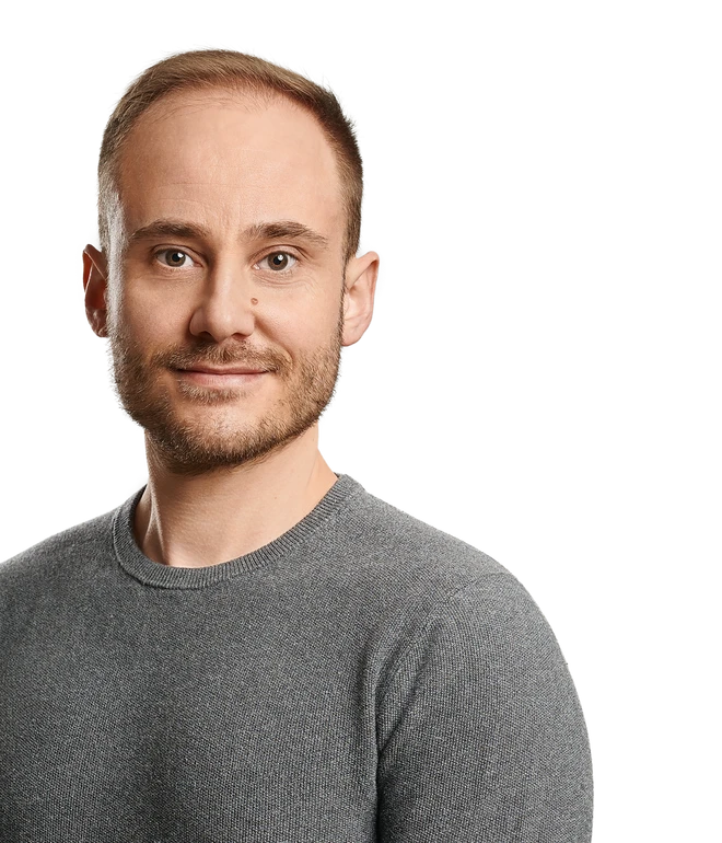 Porträt eines Mannes mit grauem Langarmshirt, blickt in die Kamera, Hintergrund mit farbigen Streifen.