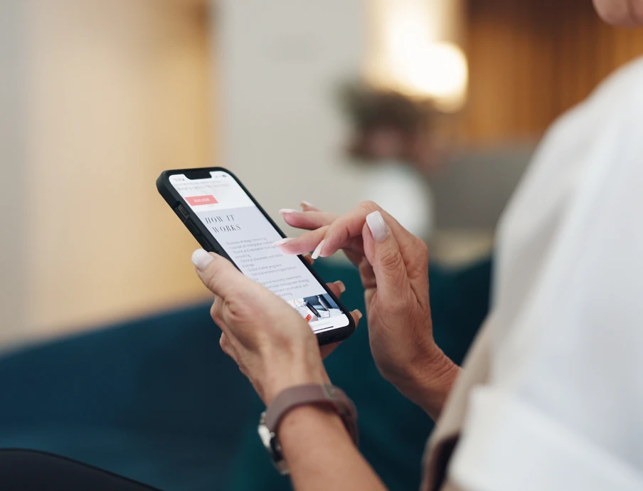 Person hält Smartphone mit beiden Händen, Nahaufnahme, Hintergrund unscharf.