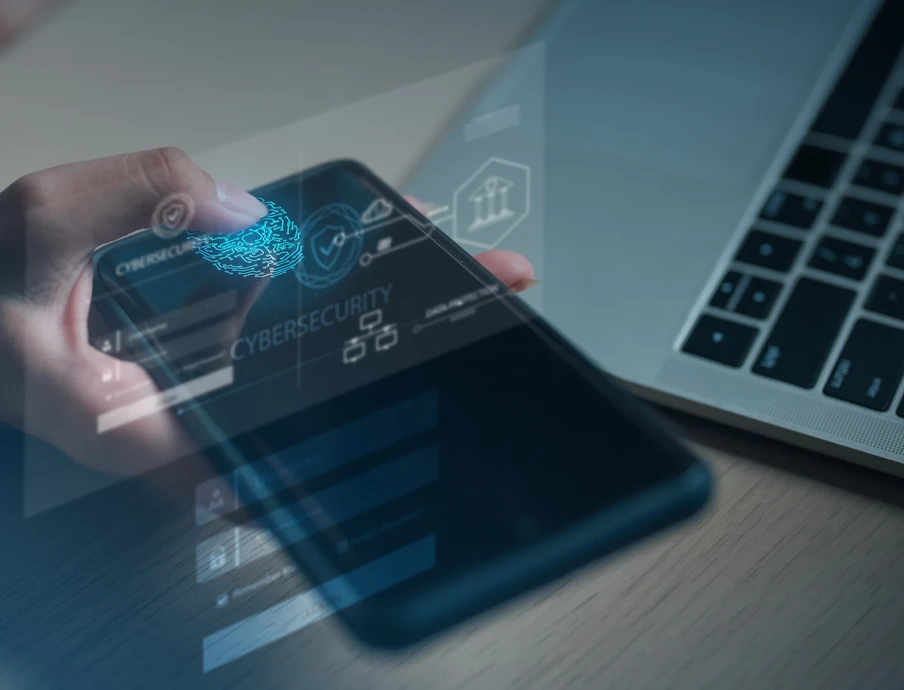 Person hält Smartphone; auf dem Display erscheinen hologrammartige Icons, Laptop im Hintergrund.