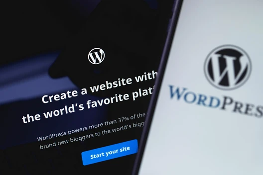 Zwei Bildschirme mit WordPress-Logo; linker Bildschirm Textzeile und blauem Button, rechter Bildschirm WordPress-Wortmarke.