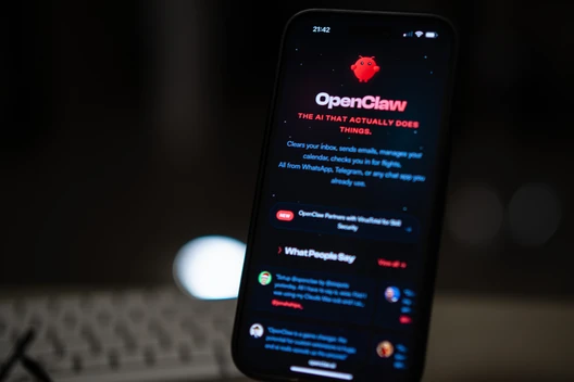 Vertikal gehaltenes Smartphone mit dunkler App-Oberfläche, rotem OpenClaw-Logo und weißen Textzeilen; unscharfer Hintergrund.