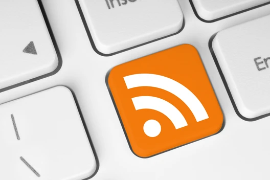 Nahaufnahme einer Computer-Tastatur; eine orangefarbene Taste mit RSS-Symbol, umgeben von weißen Tasten.